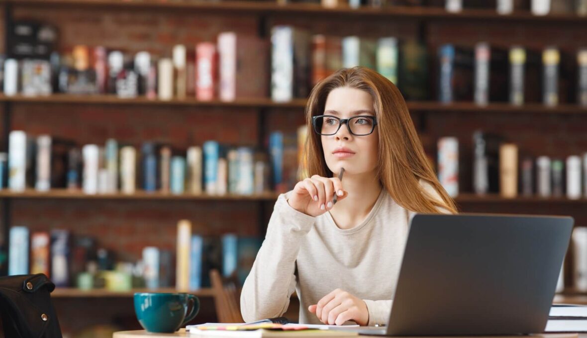 Junge Gründerin denkt am Laptop darüber nach, wie sie neue Kunden für B2B und B2C für ihr Unternehmen gewinnt.