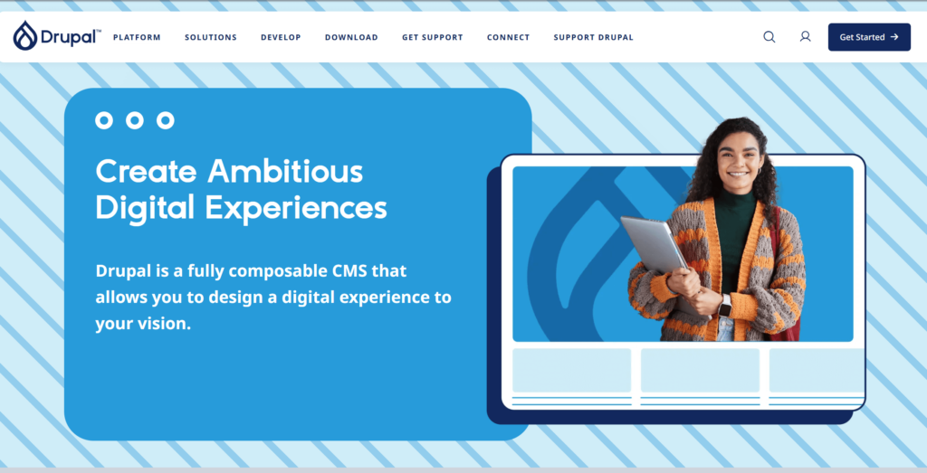 Screenshot einer Drupal-Seite mit blauem Design, dem Text „Create Ambitious Digital Experiences“ und einer Frau, die einen Laptop oder ein Tablet hält